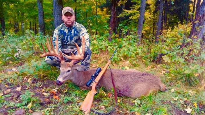 a man shows off the trophy buck he has killed