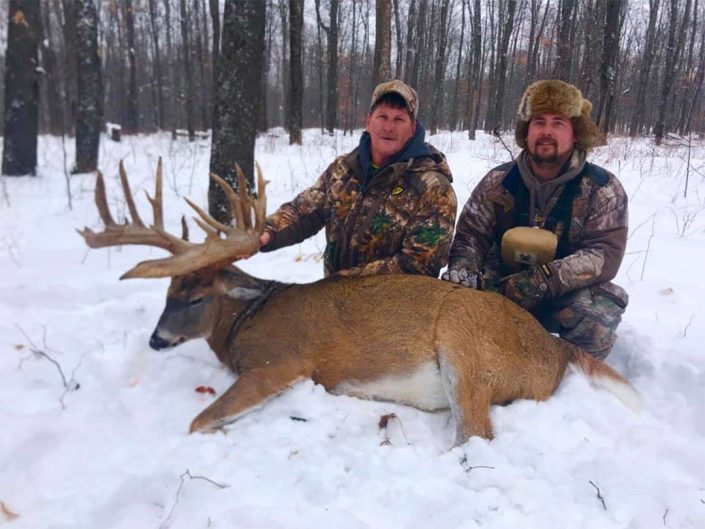 two people pose with the whitetail deer they have hunted