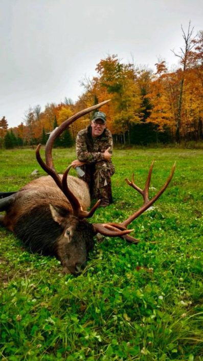 someone poses with a large trophy elk 