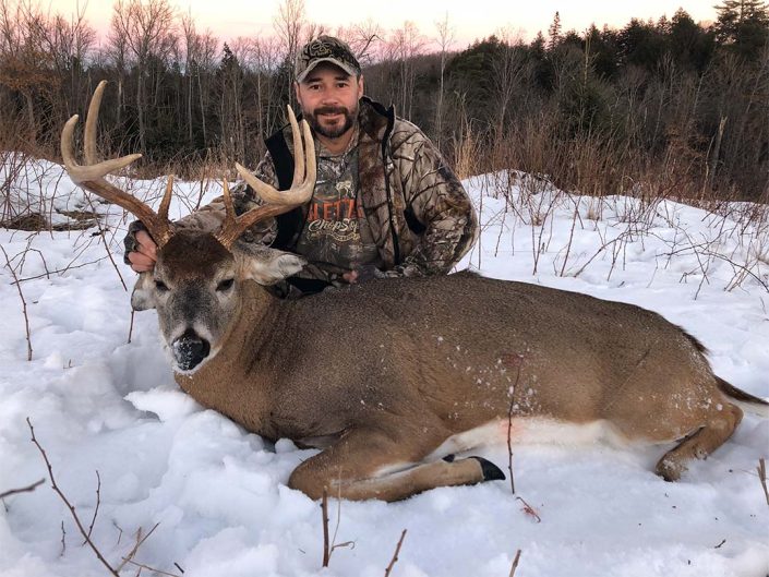 A man posing with his downed whitetail deer