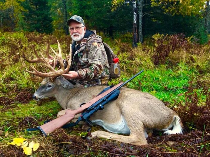A man poses with the whitetail deer he has harvested 