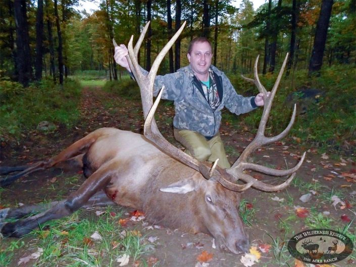 a man shows of the antlers on the elk he has harvested 