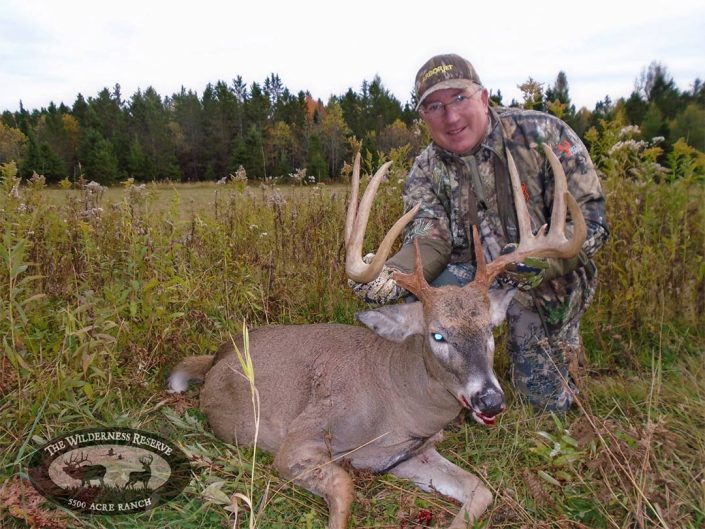 A hunter holds up a trophy buck with massive antlers