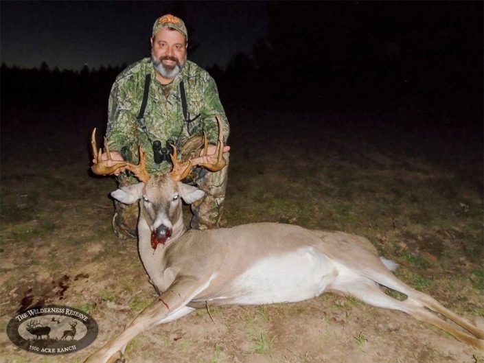 a hunter poses with a whitetail trophy buck 