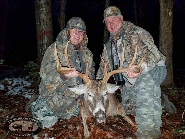 two hunters show off a whitetail buck the have killed 