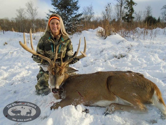 a hunter hold up her trophy whitetail kill 