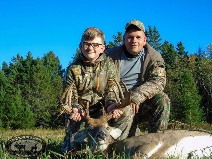 two hunters pose with a whitetail they have hunted 