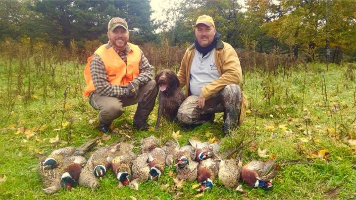 two men show off their pheasant harvest