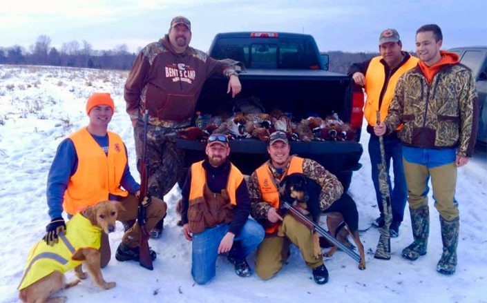 a large group poses with a truckload of pheasants they have killed