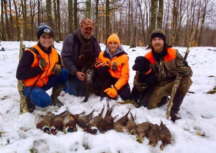 A group of four pose with some pheasants they have killed