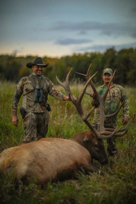 two people pose with a trophy elk 