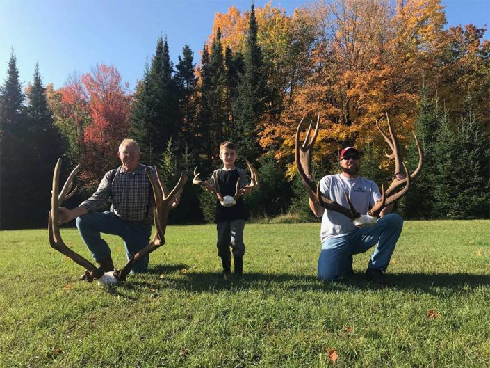 two men and a boy show off elk and whitetail antlers 