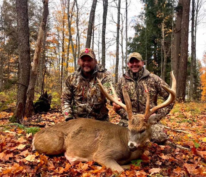 a pair of hunters show off a whitetail buck 