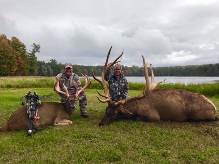 a pair of hunters show off an elk and a whitetail kill 