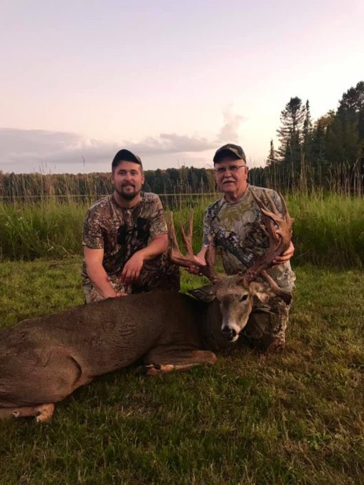 two men pose with a whitetail buck 