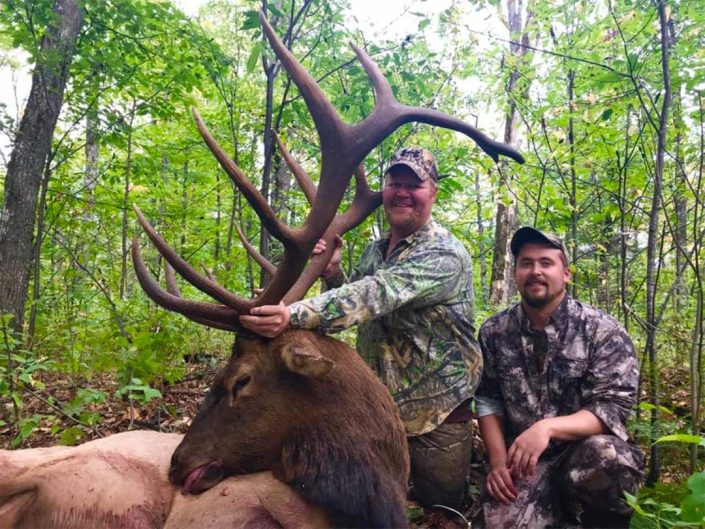 a pair of hunters pose with a trophy elk kill
