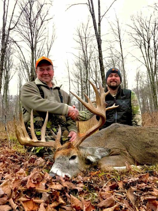 a man and a child show off their whitetail deer kill 